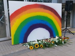 Regenbogen mit Kerzen und Blumen bei der Gedenkveranstaltung