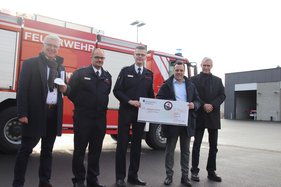 Vertreter der Stadt Euskirchen mit Feuerwehrleuten vor einem Feuerwehrfahrzeug an der Feuerwache in Euskirchen.