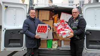 Euskirchens Bürgermeister nimmt eine Spende vor einem vollen Lieferwagen entgegen.